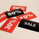 Red and black sale tags showing various discount percentages on a beige background.
